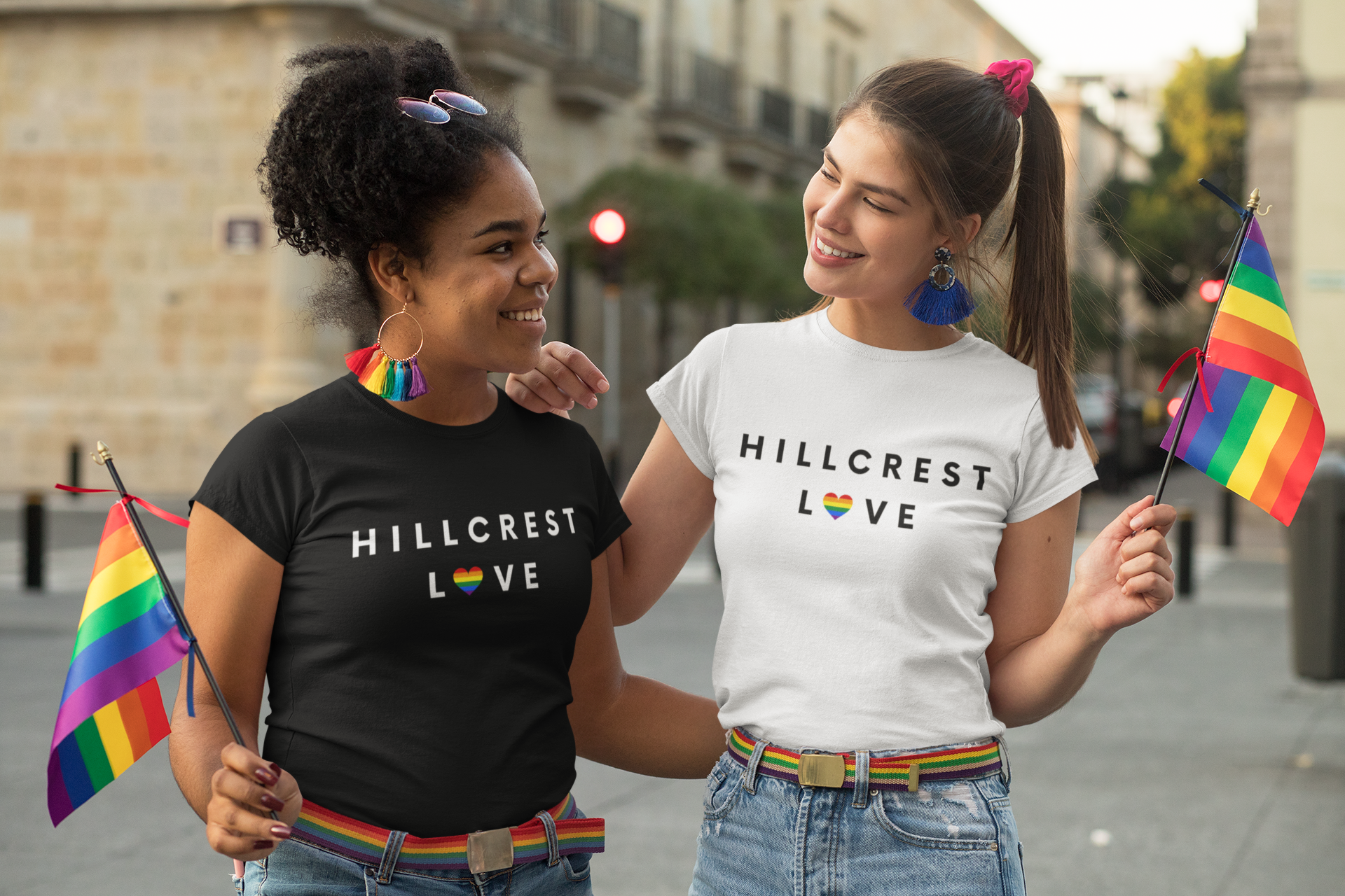 Two LBGT women holding rainbow flags in the street