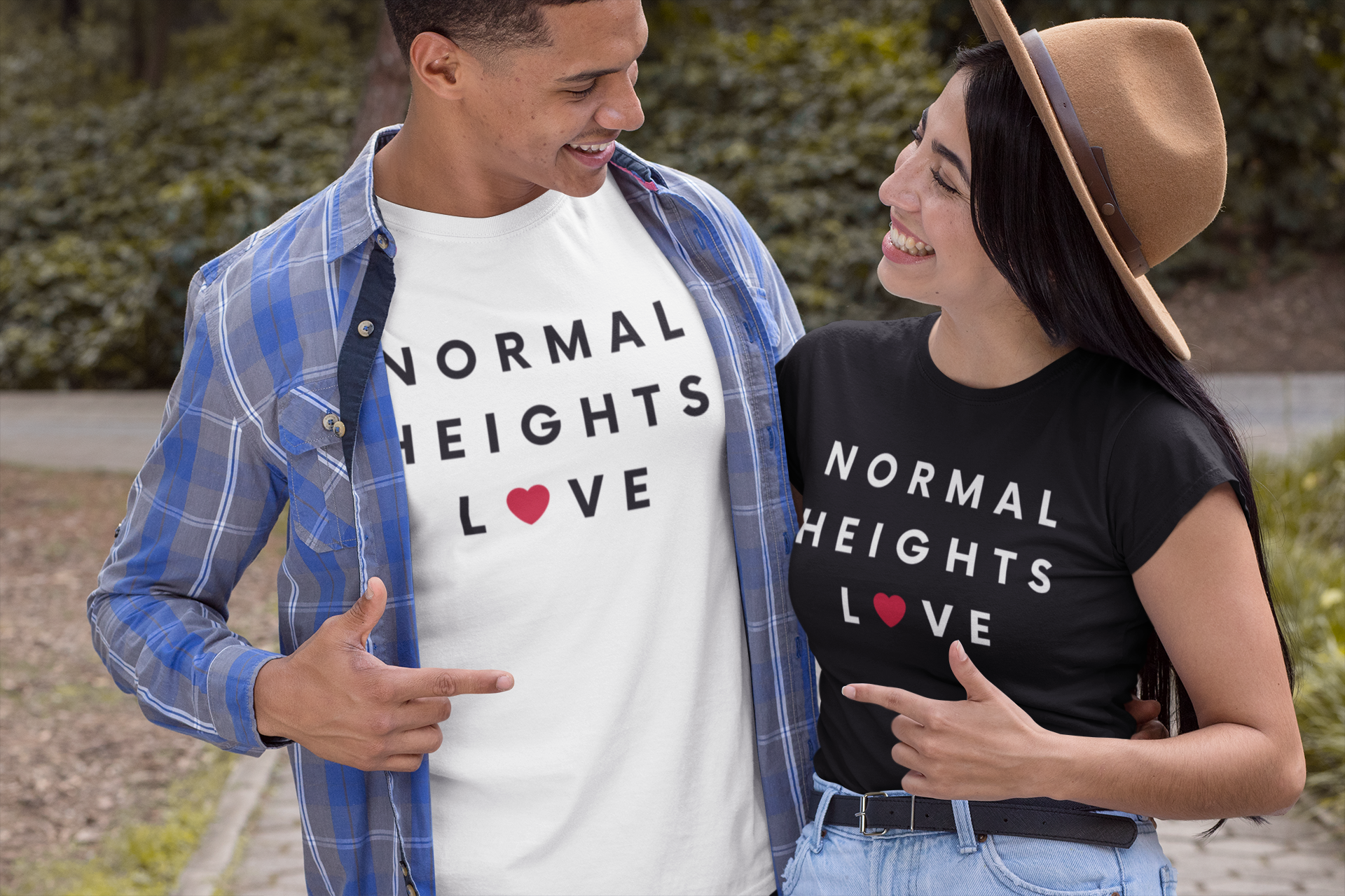 Happy couple pointing at each other smiling and wearing matching Normal Heights t-shirts.