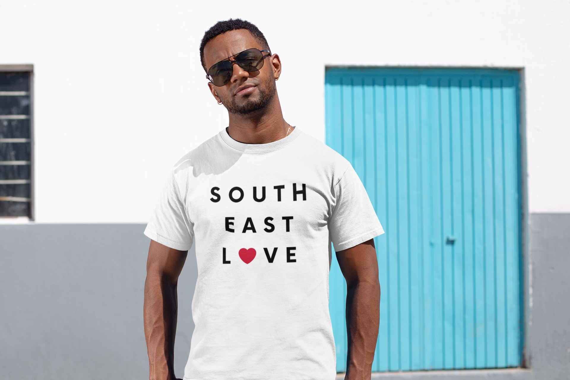 Cool guy with sunglasses standing in urban neighborhood wearing a Southeast t-shirt.