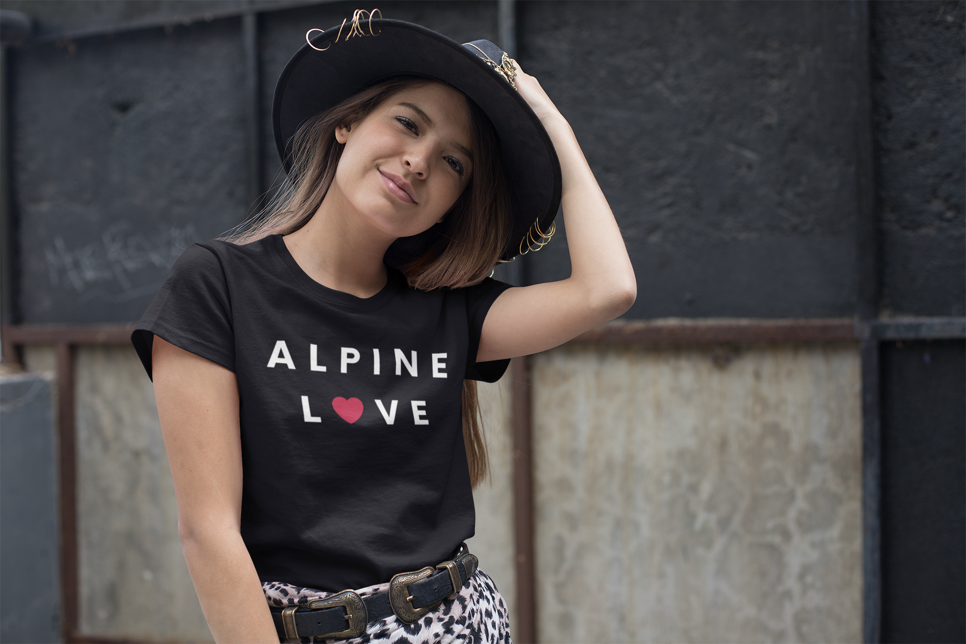 Stylish woman posing with her hand on her hat wearing an Alpine t-shirt.