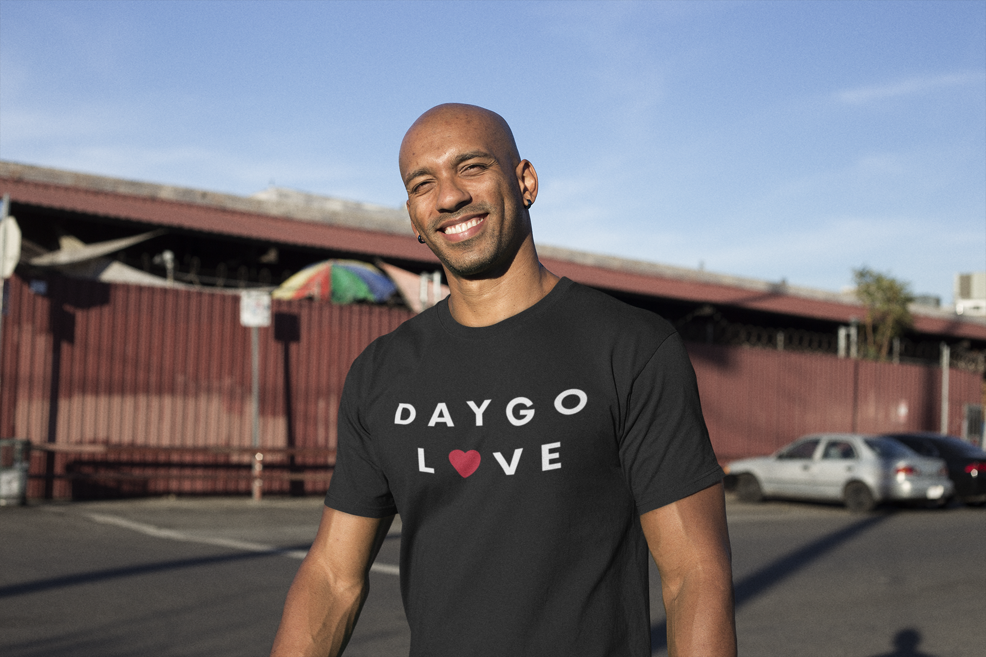 Happy black guy standing in a parking lot wearing a Daygo love tee.