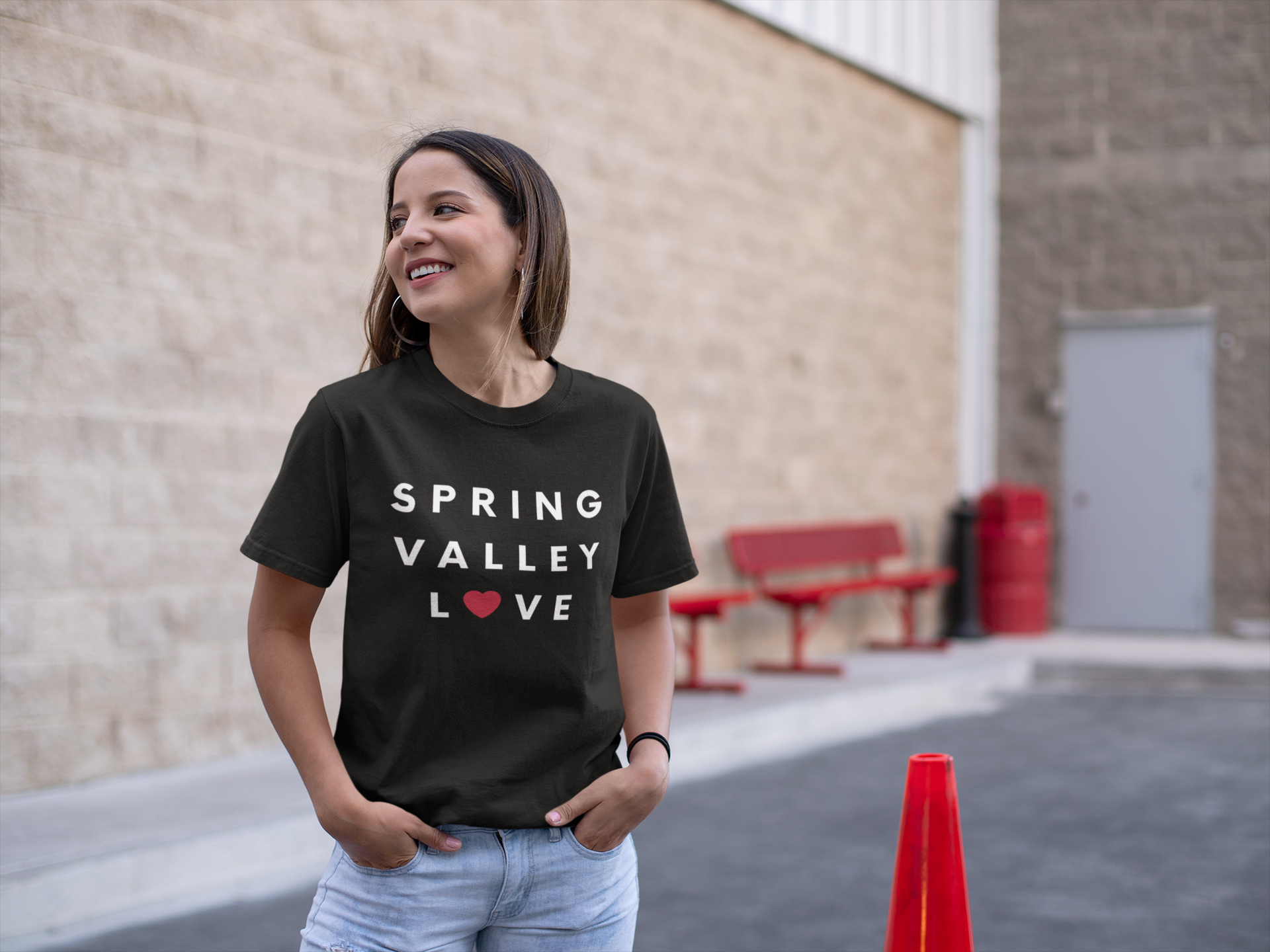 Smiling woman wearing a black Spring Valley Love t-shirt in a parking lot.
