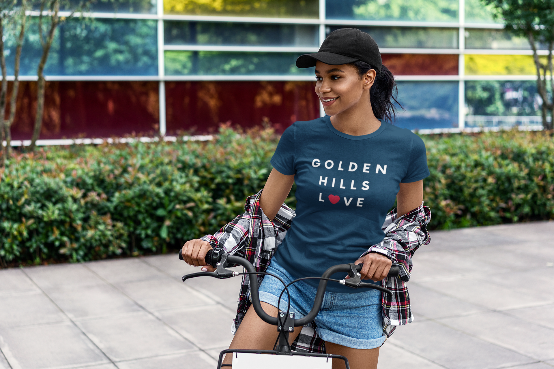 Pretty woman riding bike while wearing a blue Golden Hills Love t-shirt.