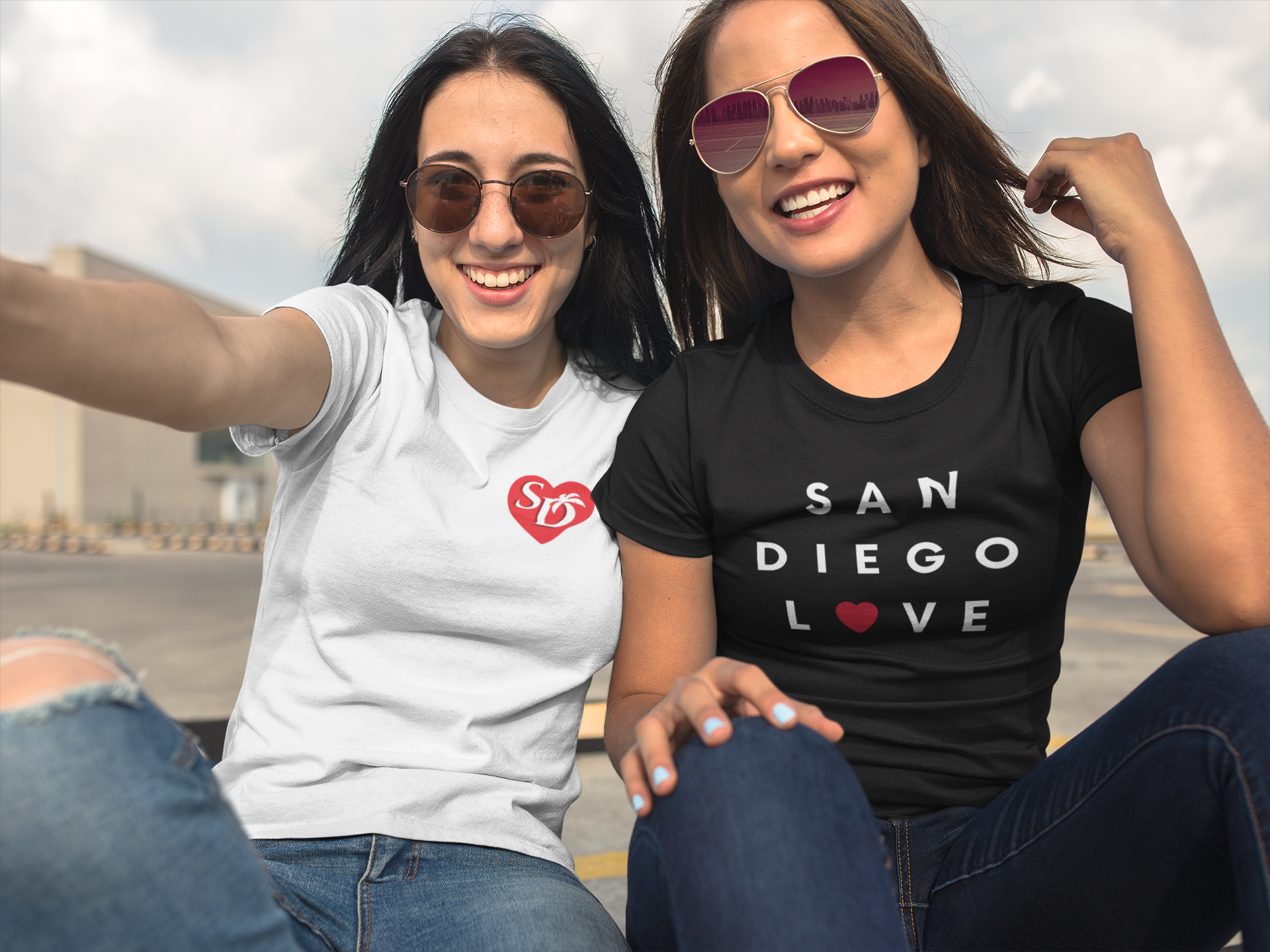 Two smiling women with sunglasses taking a selfie while wearing San Diego t-shirts.