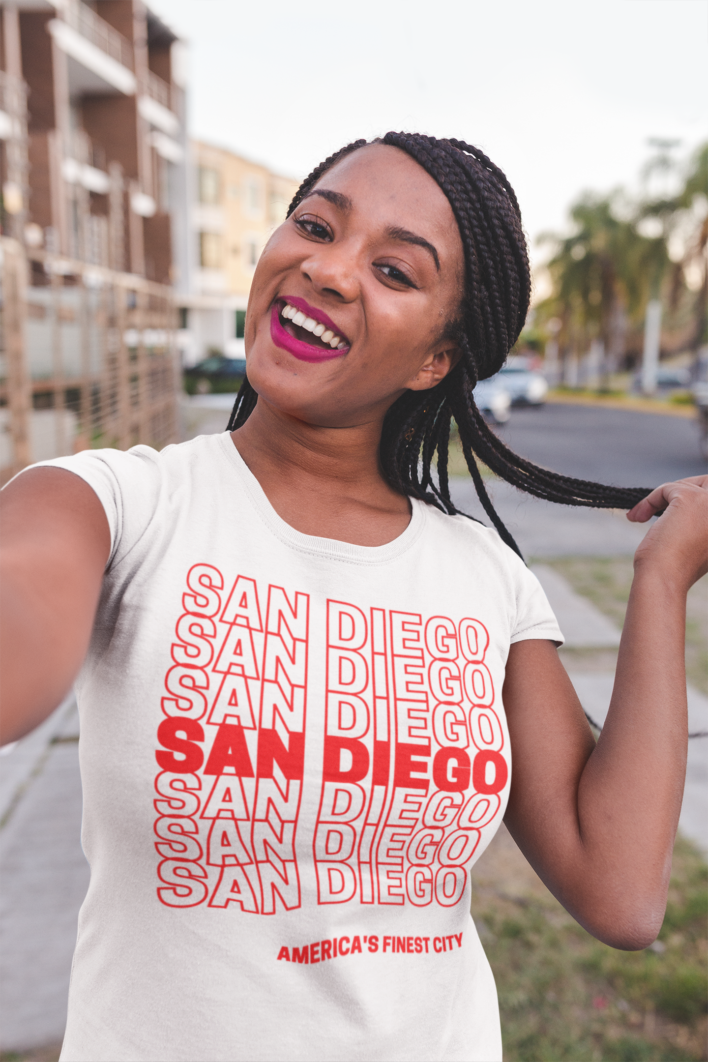 Smiling black woman taking a selfie outside wearing a red and white San Diego t-shirt.